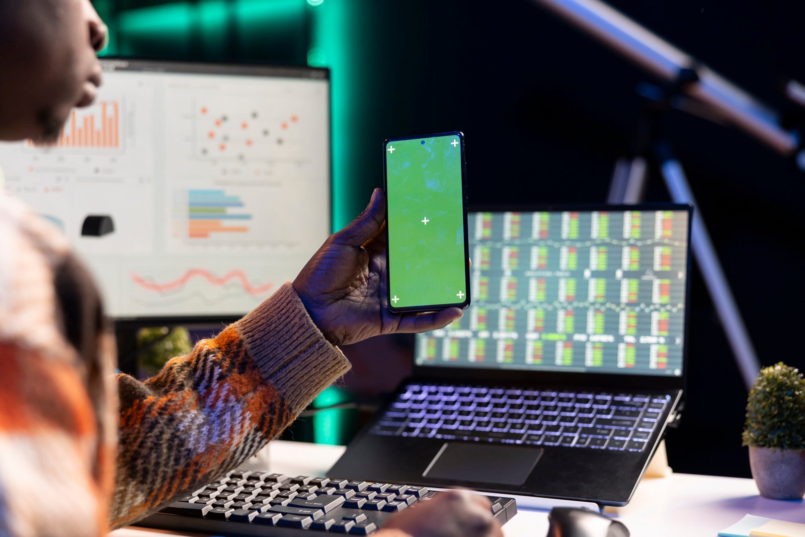 Developer working on laptop and smartphone with code and data charts