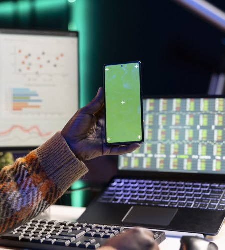 Developer working on laptop and smartphone with code and data charts