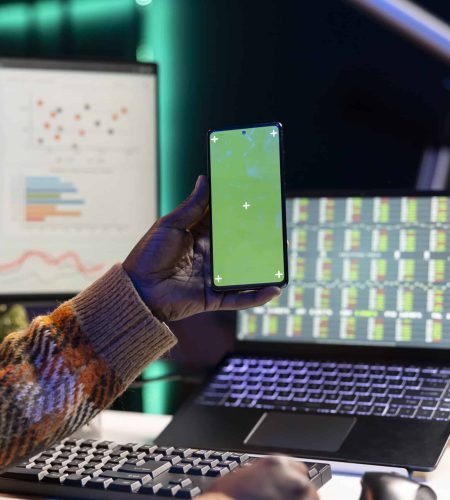 Developer working on laptop and smartphone with code and data charts