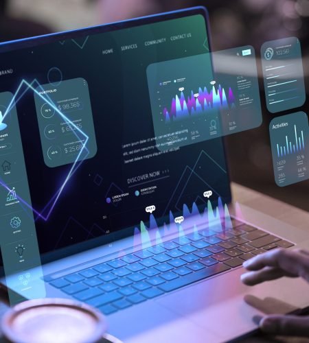 Laptop displaying digital financial analytics and holographic charts
